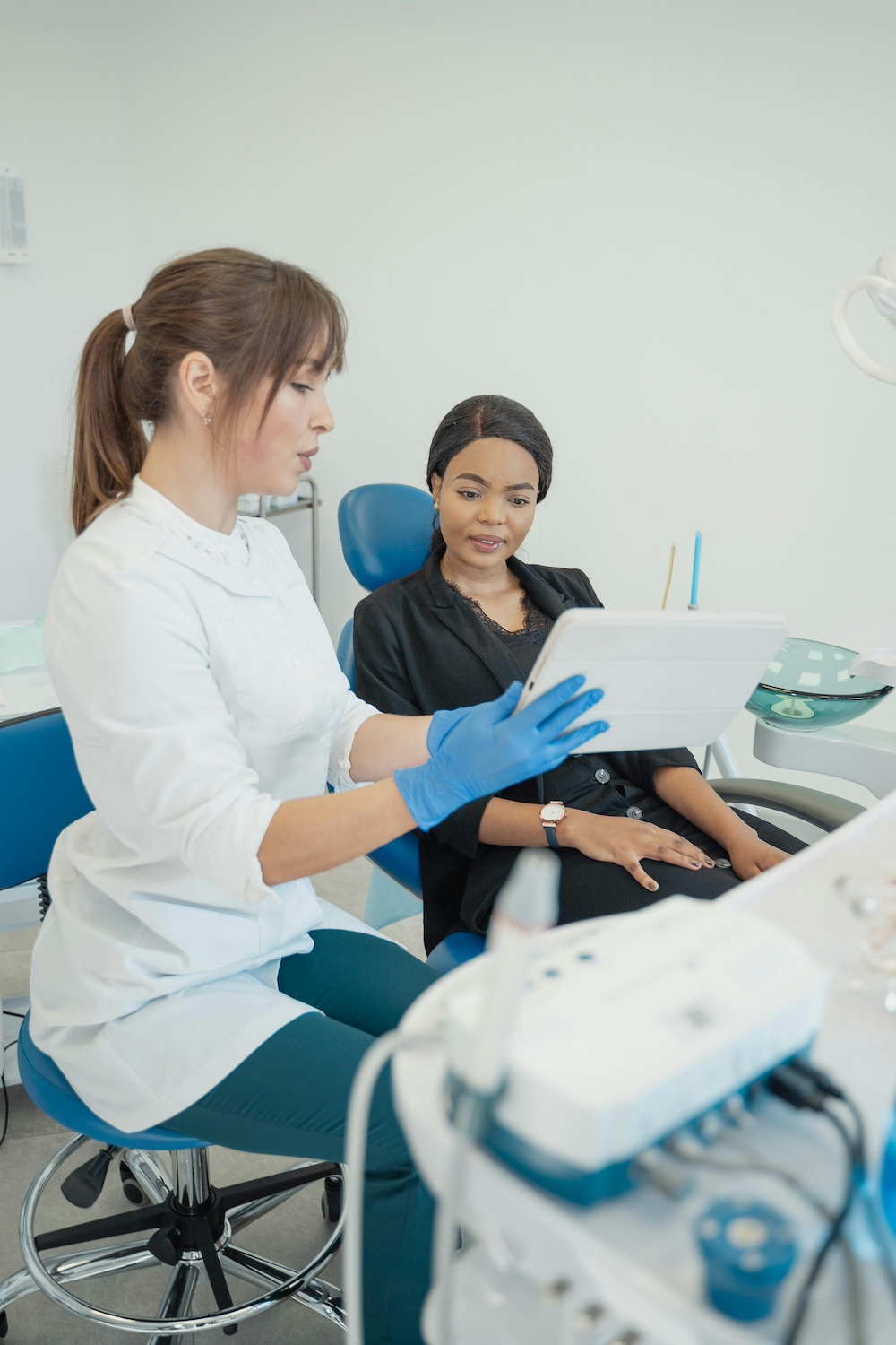 woman consulting with dentist about dental procedure looks at an ipad as dentist points